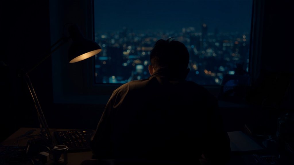 One desk lamp lit in a dark office at night, the cost of reactive website maintenance.