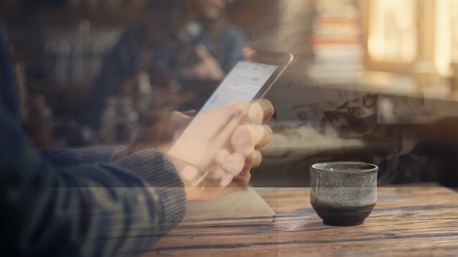 A shop owner holding a phone above the counter, checking their own website for signs it needs maintenance.